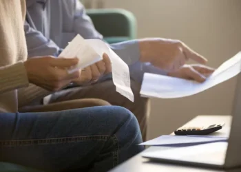 Pessoa analisando recibos e documentos relacionados a dívidas, com foco em um mutirão da Serasa que oferece descontos significativos.