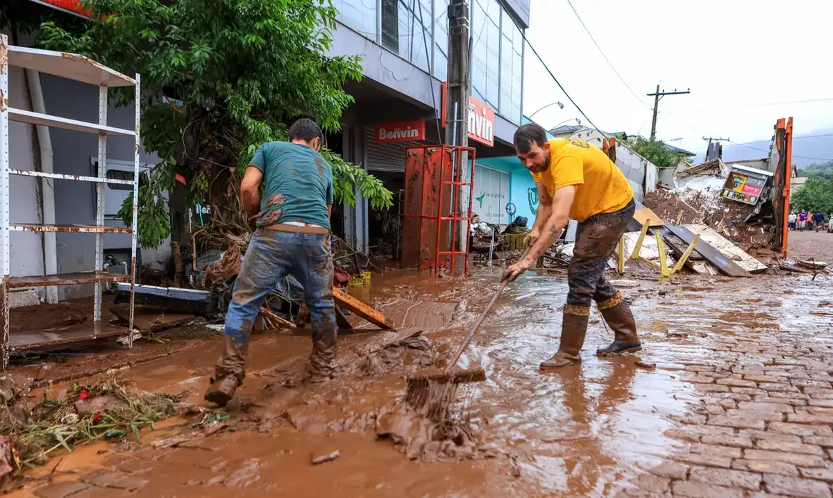 Trabalhadores removem lama após enchente em área urbana
