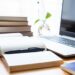 Imagem de uma mesa de trabalho com livros, caderno e laptop, simbolizando a iniciativa 'Seu Primeiro Passo' que oferece cursos gratuitos CadÚnico para jovens em 2025.