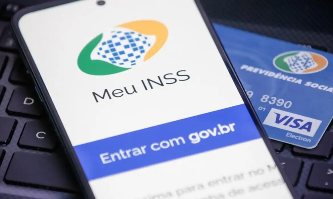 Aplicativo Meu INSS aberto em smartphone ao lado de cartão da Previdência Social