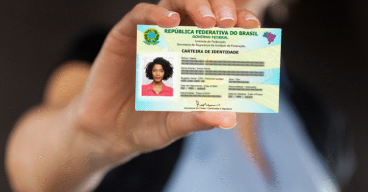 Uma mão segurando a nova Carteira de Identidade Nacional, destacando a foto e os dados.