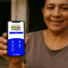 Mulher sorridente segura um celular com o aplicativo do programa Bolsa Família aberto na tela, mostrando o acesso fácil ao benefício.