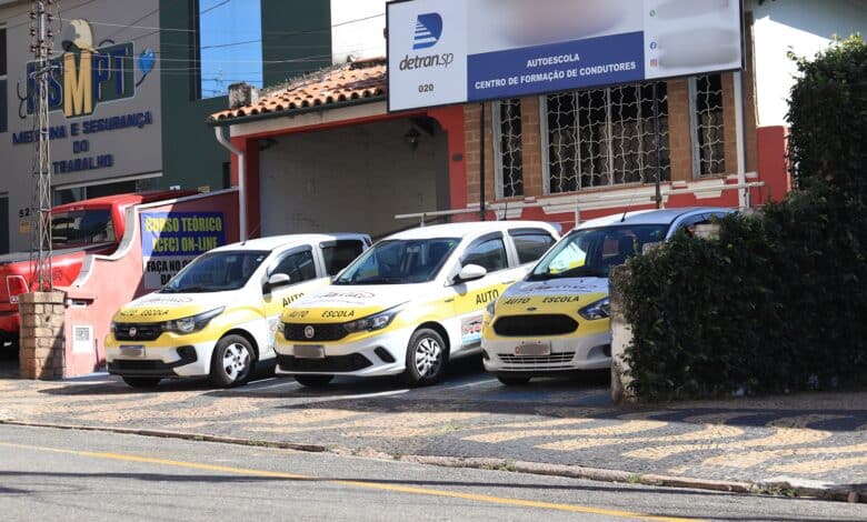 Imagem de carros de autoescola estacionados na frente de uma unidade de treinamento, representando o fim da obrigatoriedade das aulas práticas para obtenção da CNH.