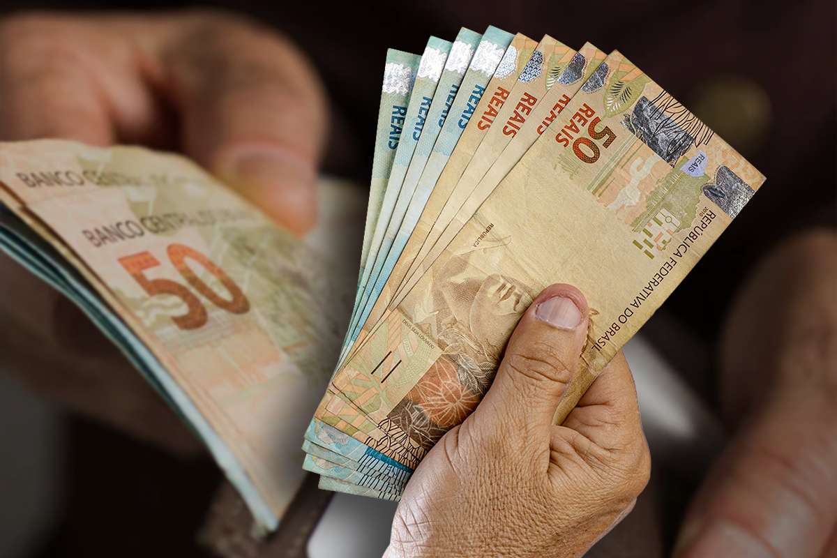 Pessoa segurando cédulas de dinheiro brasileiro em notas de 50 e 100 reais