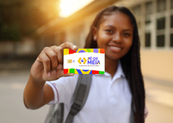 Estudante segura o cartão do programa Pé-de-Meia em frente à escola