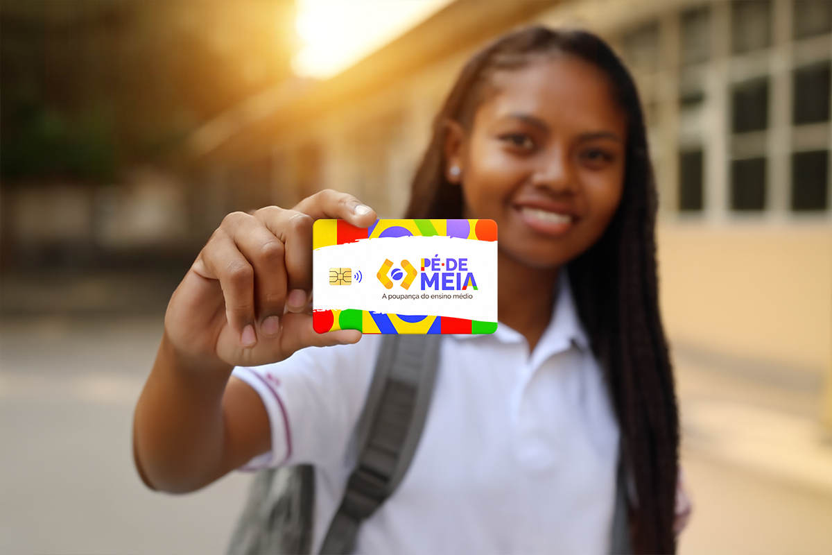 Estudante segura o cartão Pé-de-Meia com sorriso, simbolizando permanência no programa de poupança escolar 2025.