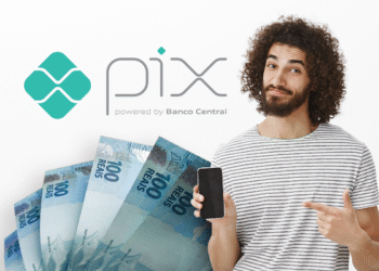 Homem com celular apontando para logo do PIX e notas de 100 reais