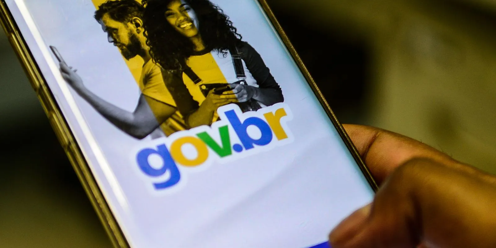 Imagem de uma pessoa acessando o portal Gov.br no smartphone, representando o acesso a serviços públicos digitais.