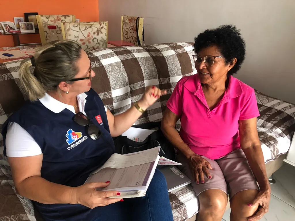 Agente social realizando visita domiciliar e atualizando informações cadastrais.
