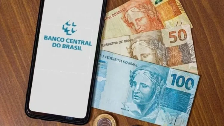 Imagem do Banco Central do Brasil mostrando notas de R$ 100, R$ 50, e moedas, com um celular exibindo o logo do Banco Central, sobre dinheiro esquecido.