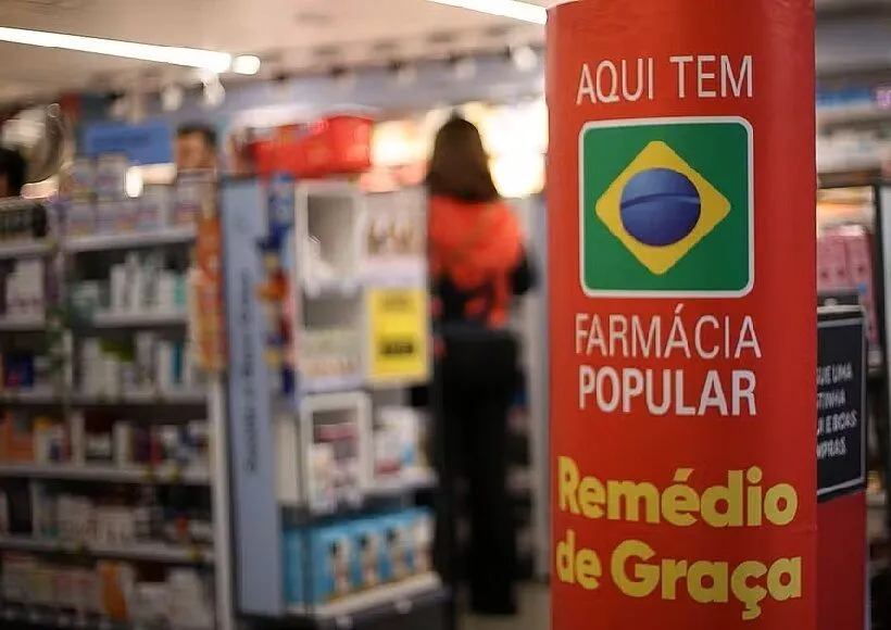 Placa indicando Farmácia Popular com o logo do Brasil, destacando a oferta de medicamentos gratuitos, no contexto de alerta sobre fraudes no programa.