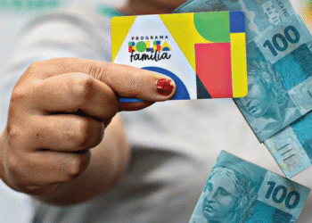 Cartão do programa Bolsa Família e notas de 100 reais, tema sobre antecipação do benefício e novas cidades na pré-lista do Governo.