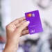 Cartão Nubank roxo sendo segurado por uma pessoa, representando a personalização e os serviços oferecidos pelo banco digital.