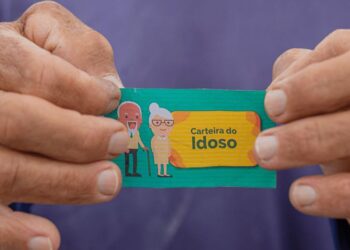 Carteira do Idoso sendo segurada por uma mão, com ilustrações de um idoso e uma idosa ao fundo. Documento utilizado para garantir descontos ou gratuidade em passagens interestaduais para pessoas com mais de 60 anos.