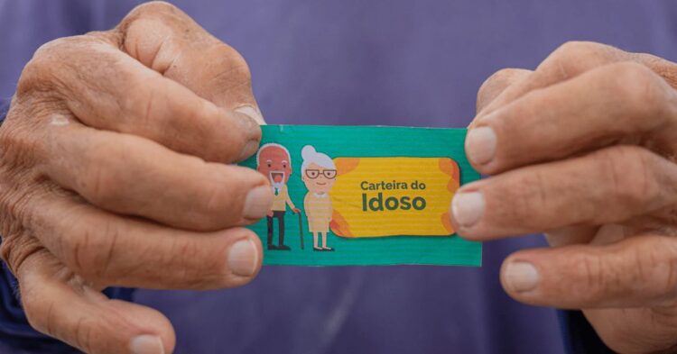 Carteira do Idoso sendo segurada por uma mão, com ilustrações de um idoso e uma idosa ao fundo. Documento utilizado para garantir descontos ou gratuidade em passagens interestaduais para pessoas com mais de 60 anos.