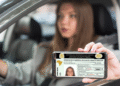 Mulher mostra CNH digital no celular dentro do carro.