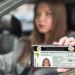 Mulher mostra CNH digital no celular dentro do carro.