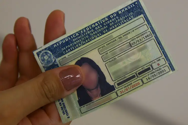 A CNH (Carteira Nacional de Habilitação) física, mostrando os dados e a fotografia de uma pessoa.