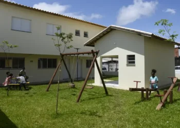 Conjunto habitacional com crianças brincando no parque em uma área residencial.