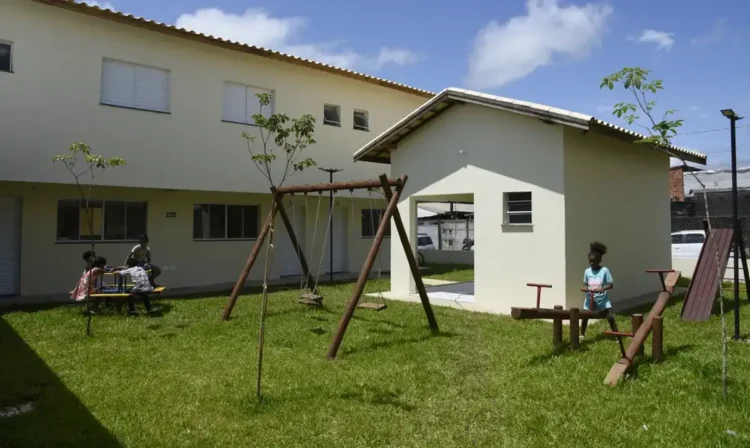 Conjunto habitacional com crianças brincando no parque em uma área residencial.