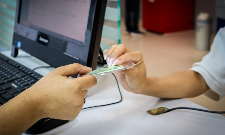 Pessoa entregando documento de identidade em atendimento no Detran