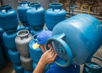 Trabalhador carregando botijão de gás, parte do processo de distribuição no programa Gás para Todos.
