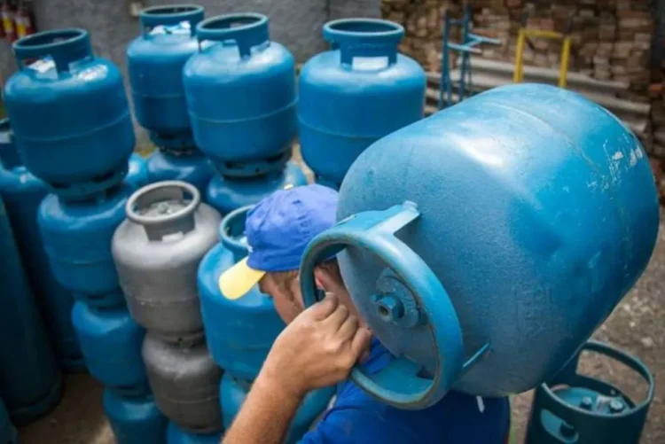 Trabalhador carregando botijão de gás, parte do processo de distribuição no programa Gás para Todos.