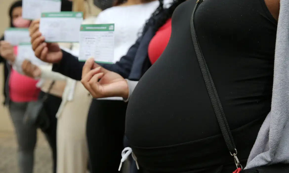 Gestantes segurando documentos enquanto aguardam atendimento