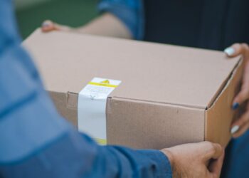 Entregador segurando caixa com alerta de fraude de golpe de presente.