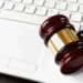 Gavel sobre teclado de laptop, representando leilão de veículos do Detran, com motos a partir de R$ 700.