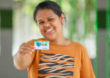 Mulher sorrindo e segurando cartão do Mães de Pernambuco.