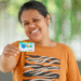 Mulher sorrindo e segurando cartão do Mães de Pernambuco.