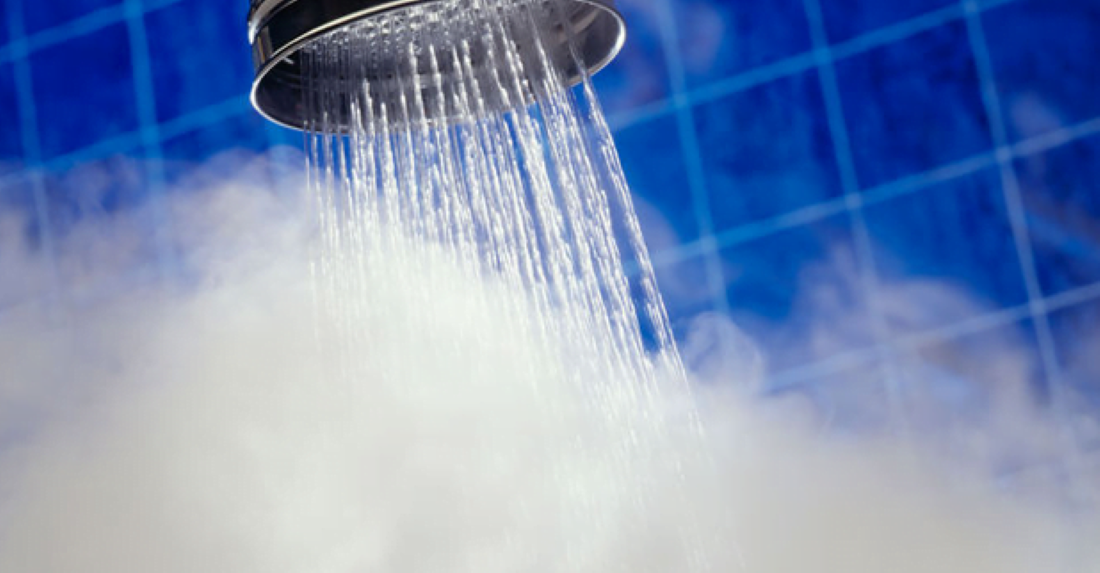 Chuveiro com vapor, simbolizando banho quente no inverno sem desperdício de energia.