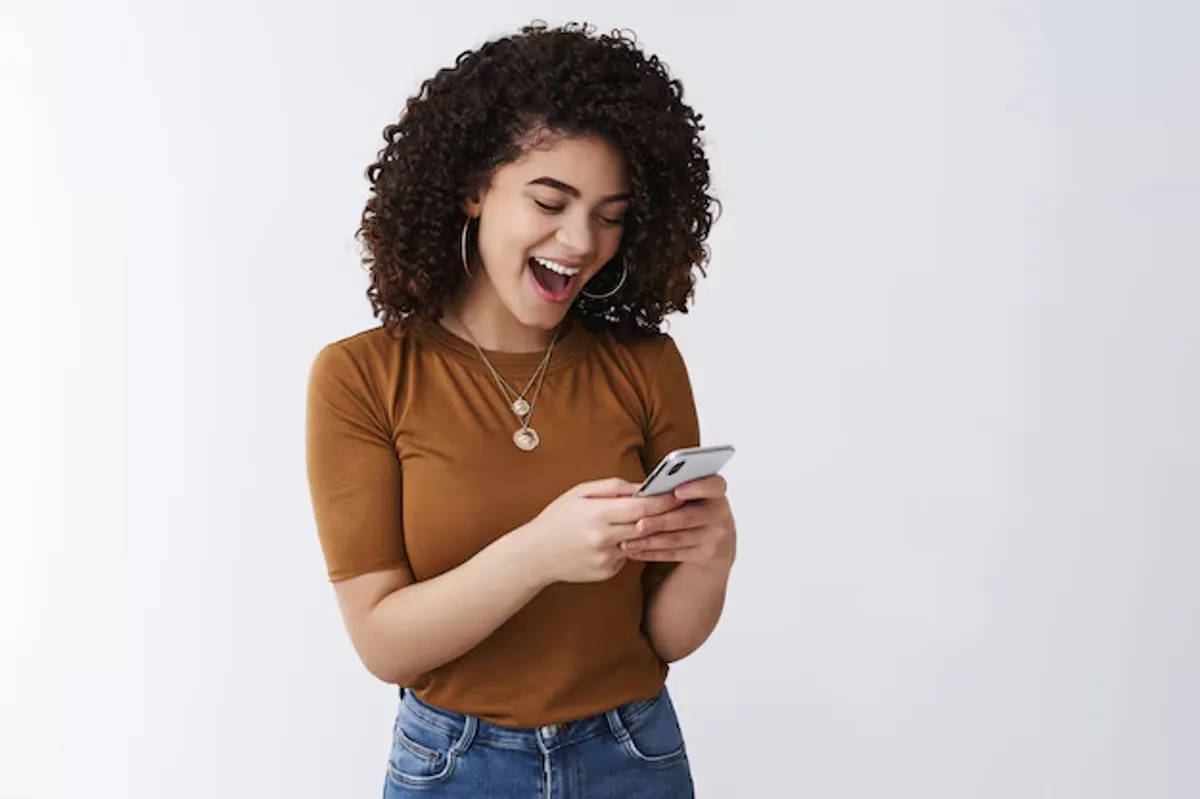 Pessoa sorrindo e interagindo com o celular, ilustrando como é fácil obter a nova Carteira Nacional de Identidade.
