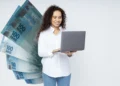 Mulher sorrindo com laptop e notas de 100 reais ao fundo, ilustrando o pagamento do último lote do PIS/PASEP em 2025.