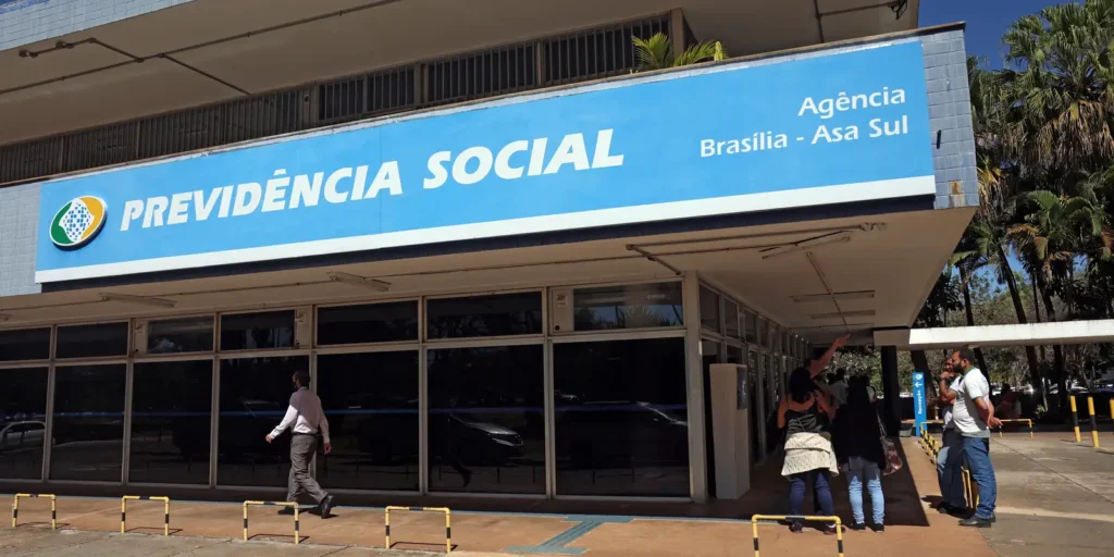 Vista frontal da fachada da Agência da Previdência Social em Brasília - Asa Sul, com o logo e o nome 'PREVIDÊNCIA SOCIAL' em destaque, referenciando o novo programa PGB.