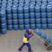Trabalhador transportando botijões de gás em área de distribuição