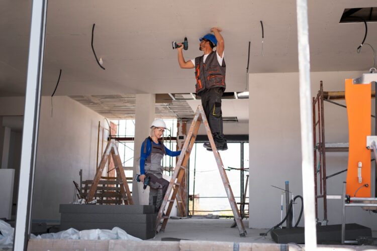 Trabalhadores realizando reforma em construção civil com equipamentos profissionais