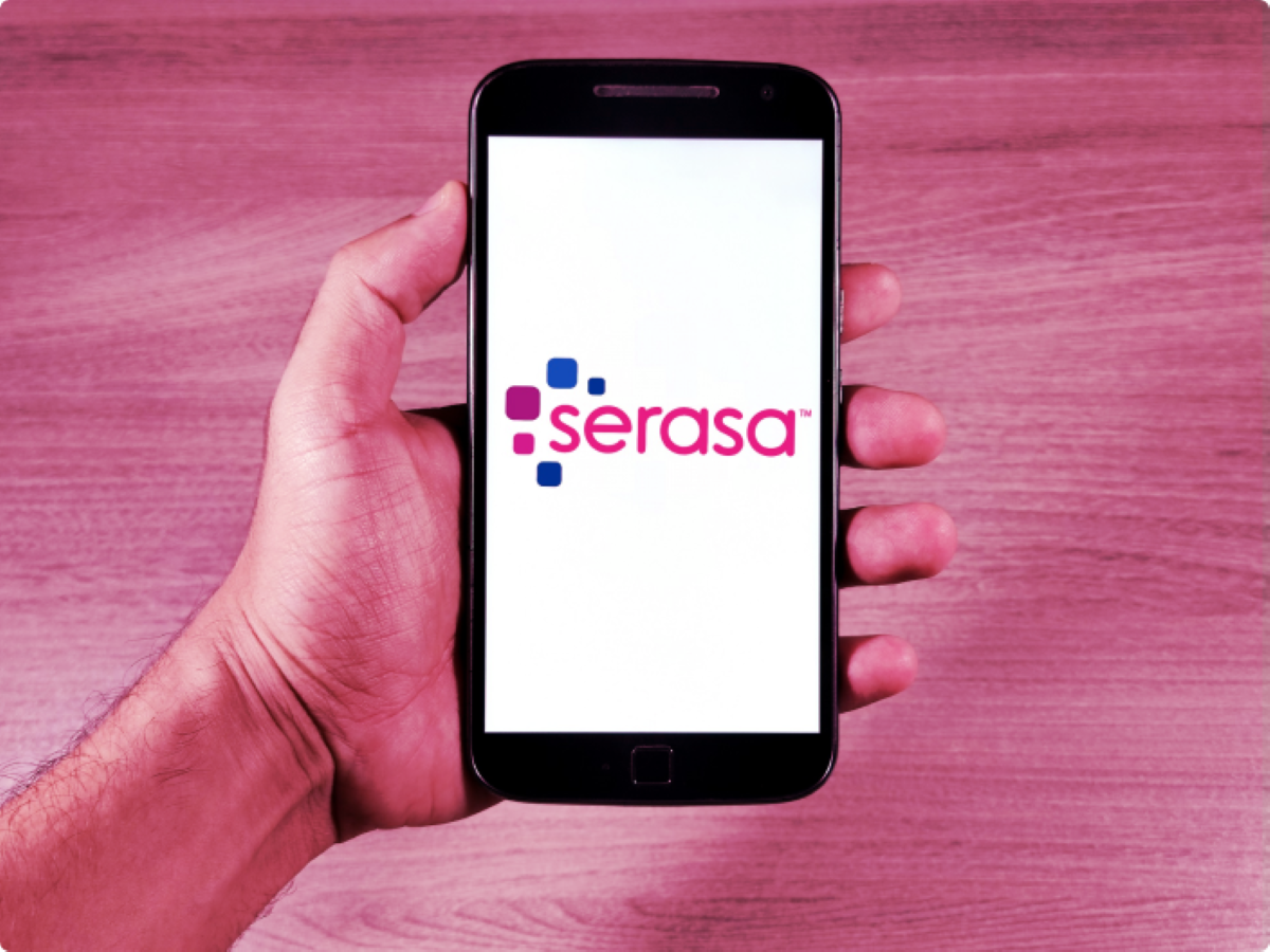 Mão segurando celular com o aplicativo da Serasa na tela.