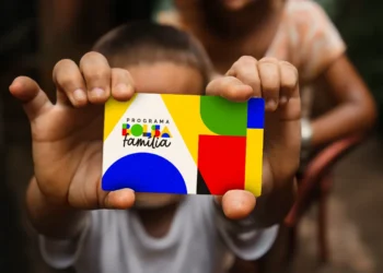 Criança segurando o novo cartão do Programa Bolsa Família com cores vibrantes