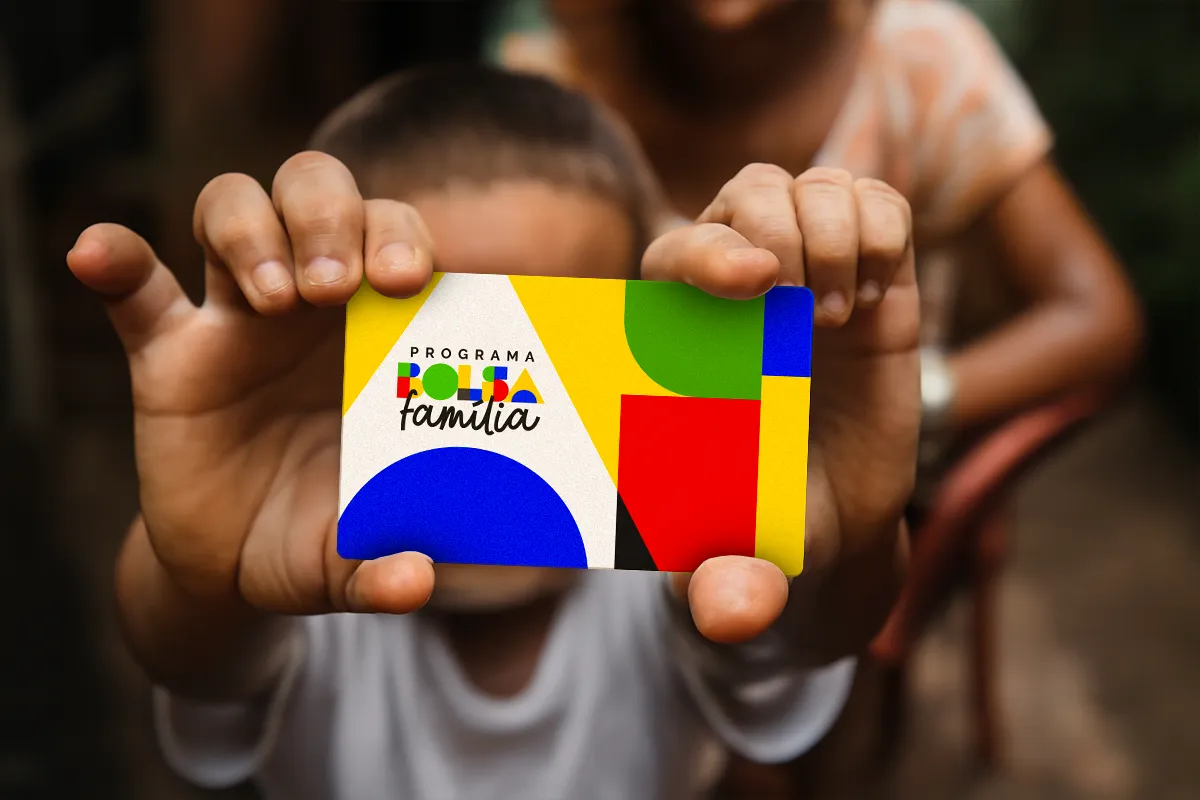 Duas crianças segurando juntas o cartão do Bolsa Família, representando os beneficiários do programa social.