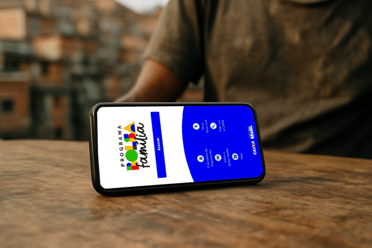 Celular exibindo aplicativo do Bolsa Família sobre mesa de madeira