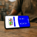 Celular exibindo aplicativo do Bolsa Família sobre mesa de madeira