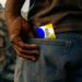 Carteira social do Bolsa Família sendo guardada no bolso traseiro de uma calça jeans, simbolizando a segurança e a posse do benefício.
