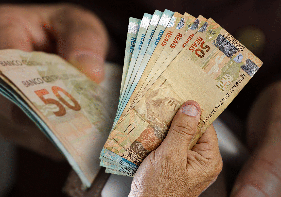 Mãos segurando notas de cinquenta reais, ilustrando o reajuste do salário mínimo com base na inflação e no crescimento do PIB.