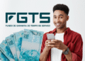 Homem feliz usando celular com notas de 100 reais ao lado, representando saque do FGTS