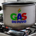 Panela sobre um fogão com a chama acesa, e o logo do "Gás do Povo" estampado na lateral, simbolizando o novo programa social para famílias de baixa renda.