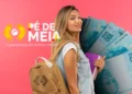 Estudante com livros e mochila, representando os beneficiários do Programa Pé-de-Meia, com notas de 100 reais ao fundo.