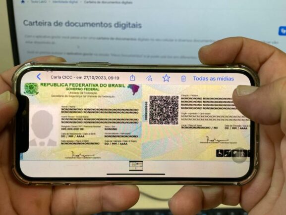 Uma pessoa segura um celular que exibe a nova Carteira de Identidade Nacional (CIN) com um QR Code visível, demonstrando o documento em formato digital.