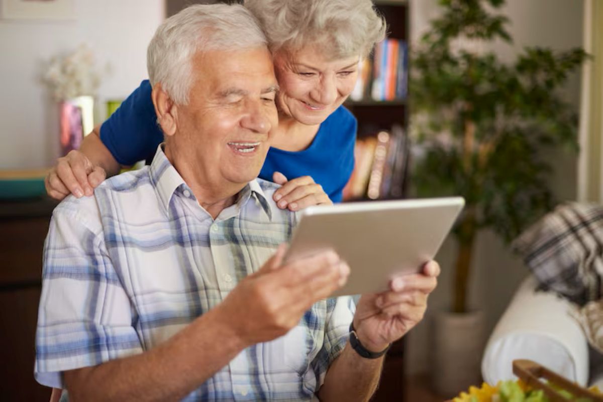 Casal de idosos feliz utilizando um tablet para realizar procedimentos online, como a Prova de Vida do INSS.